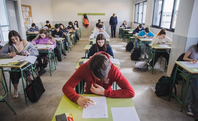 Alumnos y alumnas de secundaria, realizando un examen en clase bajo la supervisión de su profesor.