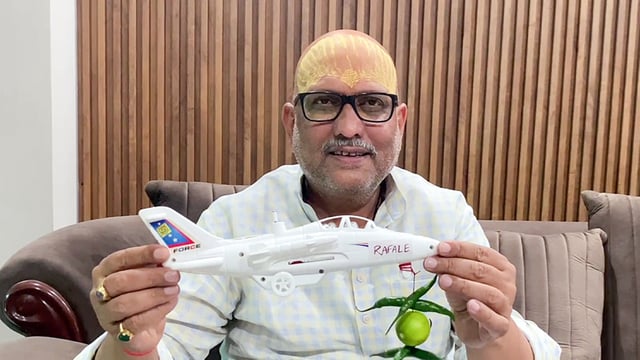 Uttar Pradesh Congress President Ajay Rai while speaking to media shows a 'toy plane' with Rafale written on it and lemon-chillies hanging in it, in Varanasi on Sunday. 