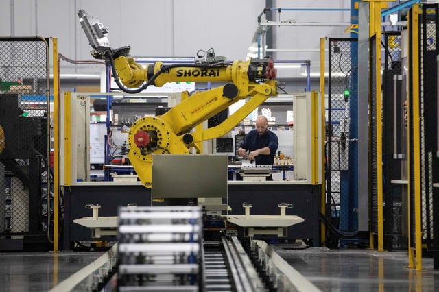A factory worker works on an aircraft part, as the robot arm of an automated five-axis cell operates autonomously nearby, at Abipa Canada, in Boisbriand, Quebec, Canada May 10, 2023. REUTERS/Evan Buhler/File photo