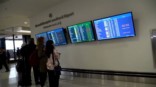Passengers look at departure and arrival boards at Newark Liberty International Airport on May 4, 2025.