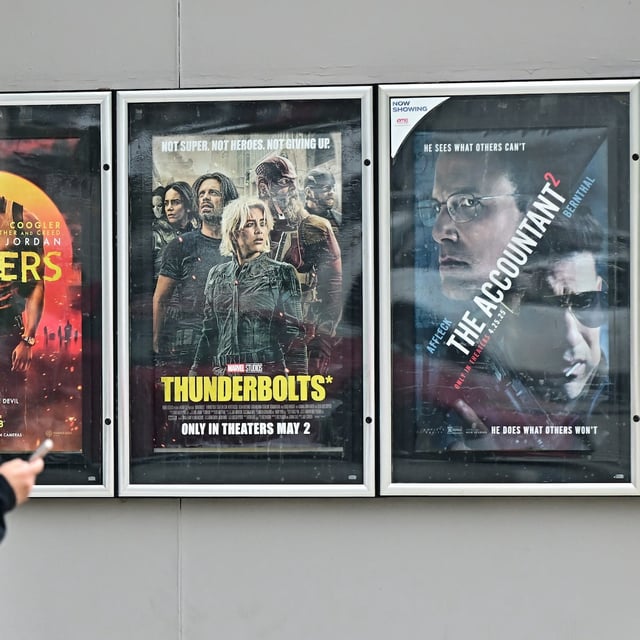A man walks past movie posters at at AMC Theater in Montebello, California on May 5, 2025. US President Donald Trump said Sunday he was ordering new tariffs on all films made outside the United States, claiming Hollywood was being "devastated" by a trend of US filmmakers and studios working abroad. The announcement comes as the White House is coming under mounting criticism over its aggressive trade policies that have seen Trump impose sweeping tariffs on countries around the globe. (Photo by Frederic J. BROWN / AFP) (Photo by FREDERIC J. BROWN/AFP via Getty Images)