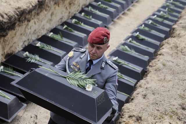 with the remains of fallen German soldiers of WWII to the grave during a funeral service at a memorial site for fallen soldiers in Halbe, Germany, Wednesday, April 30, 2025. (AP Photo/Ebrahim Noroozi)