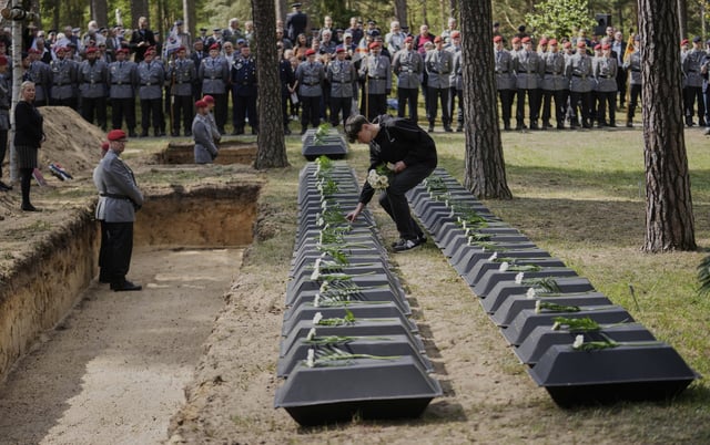 A student pays tribute to the small coffins with the remains of fallen German soldiers of WWII during a funeral service at a memorial site for fallen soldiers in Halbe, Germany, Wednesday, April 30, 2025. (AP Photo/Ebrahim Noroozi)