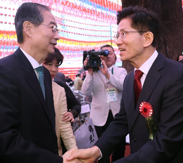 Kim Moon-soo (right), presidential candidate of the South Korean People Power Party, shakes hands with independent preliminary presidential candidate Han Duck-soo at Jogye Temple in Seoul on Monday. Photo: dpa