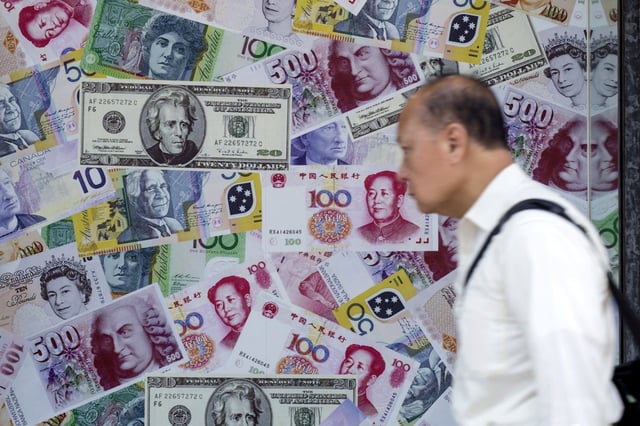 A man walks past an advertisement promoting China's renminbi (RMB) or yuan, U.S. dollar and Euro exchange services at foreign exchange store in Hong Kong, China, August 13, 2015. German Bund yields edged up on Thursday following efforts by China's central bank to slow a sharp descent of the yuan that has prompted investors this week to seek safe-haven assets. REUTERS/Tyrone Siu/File Photo