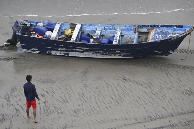 A Del Mar lifeguard looks over a capsized boat on the beach Monday, May. 5, 2025, in at Torrey Pines State beach in San Diego, Calif. (AP Photo/Denis Poroy)