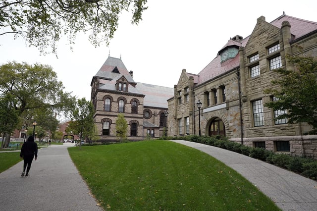 A passer-by walks along a path on the campus of Brown University, in Providence, R.I., Monday, Oct. 12, 2020. (AP Photo/Steven Senne)