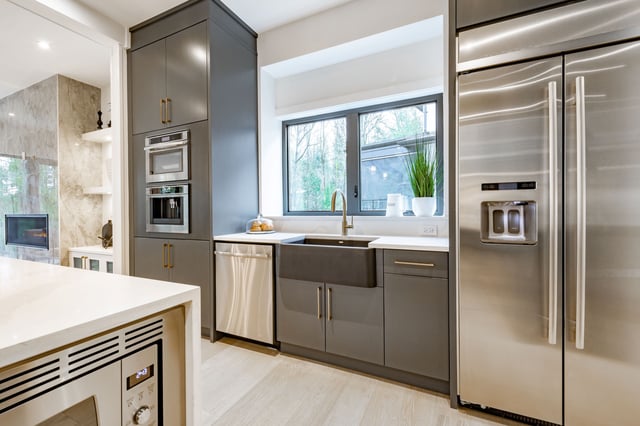 A large and spacious kitchen has hardwood floors, stainless steel appliances, marble countertops, and grey cabinets.