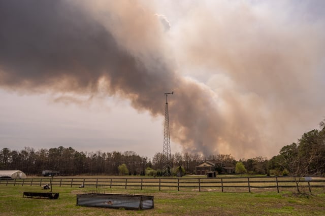 A wildfire burns in the distance behind Argos Farm on April 24, 2025, in Forked River, New Jersey. (Photo by Adam Gray/Getty Images)