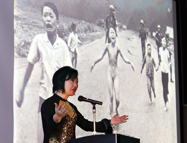 Kim Phuc stands beside the 1972 Pulitzer winning photograph of her running naked and burnt by napalm during the Vietnam War, as she addresses delegates during a 2013 conference in Nagoya, Japan