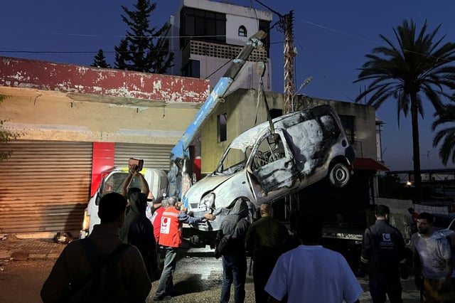 Lebanese soldiers stand guard as a recovery crew removes the vehicle in which a Hamas commander was killed in an Israeli strike.