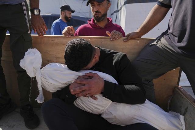 A Palestinian man embraces the body of his 5-year-old son, Adam Namrouti, who was killed in an overnight Israeli airstrike on a UN school used as a shelter, ahead of his burial at Al-Aqsa Hospital in Deir al-Balah, in the central Gaza Strip, Wednesday, May 7, 2025. (AP Photo/Abdel Kareem Hana)