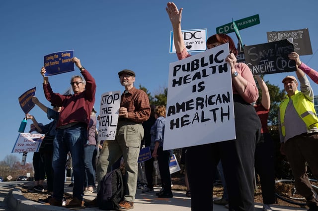 People protesting personnel cuts at the Centers for Disease Control (CDC) hold signs outside the organization's main headquarters on March 12, 2025, in Atlanta, Georgia.