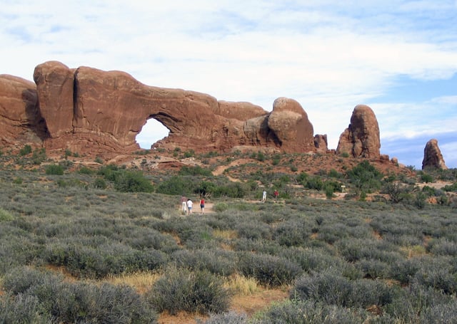 FILE - Visitors to the Arches National Park walk towards a sandstone formation called South Window in Moab, Utah, on Aug. 27, 2005. (AP Photo/Beth Harpaz, File)