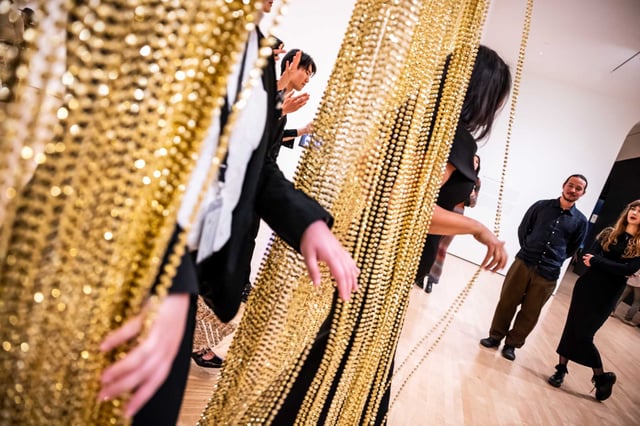 Party guests walk through a gold bead curtain during the Art Bash fundraiser for SFMOMA in San Francisco, on April 23, 2025.  The San Francisco Museum of Modern Art laid off 29 employees on Wednesday, May 7, in a move that has sparked sharp backlash from workers and their representatives.