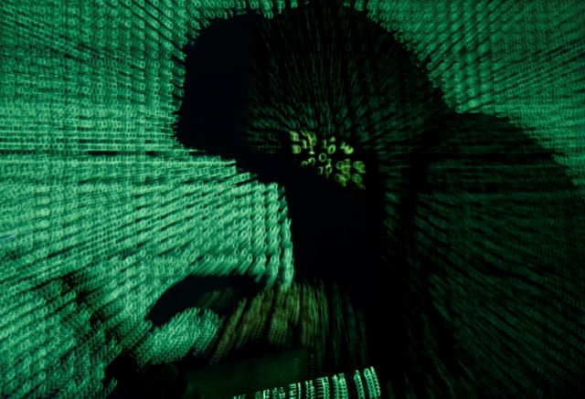 A man holds a laptop computer as cyber code is projected on him in this illustration picture taken on May 13, 2017. Capitalizing on spying tools believed to have been developed by the U.S. National Security Agency, hackers staged a cyber assault with a self-spreading malware that has infected tens of thousands of computers in nearly 100 countries. REUTERS/Kacper Pempel/Illustration