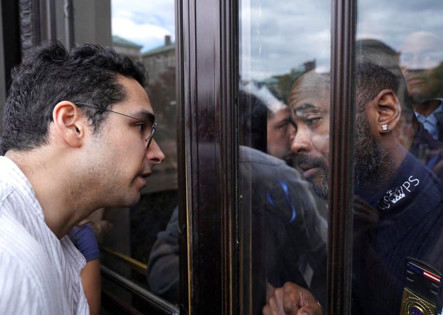 A man faces a member of Columbia University Public Safety through a door during a pro-Palestinian protest at Butler Library on the campus of Columbia University in New York, U.S., May 7, 2025.   REUTERS/Ryan Murphy