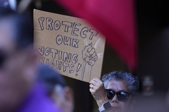 FILE - A supporter waves a sign at a news conference, Aug. 26, 2024, in San Antonio. (AP Photo/Eric Gay, file)
