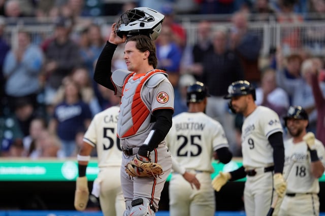 Baltimore Orioles catcher Adley Rutschman (35), front, stands at the plate as Minnesota Twins&#39; Byron Buxton (25), back, celebrates his 3-run home run with teammates during the third inning of a baseball game Wednesday, May 7, 2025, in Minneapolis. (AP Photo/Abbie Parr)