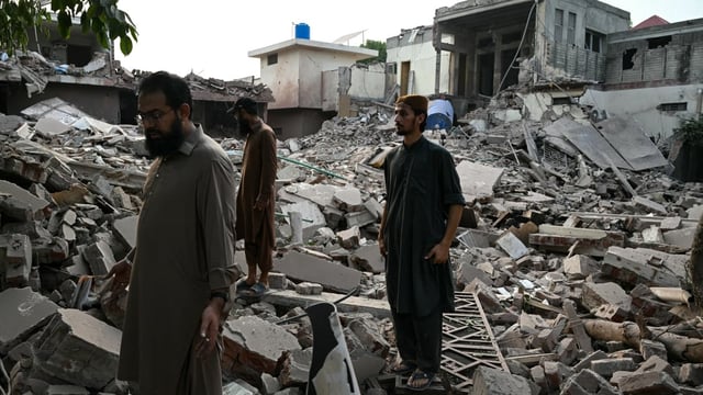 Locals stand on the debris of destroyed structures at the Government Health and Educational complex in Muridke about 30 kilometres from Lahore, on May 7, 2025, after Indian strikes.