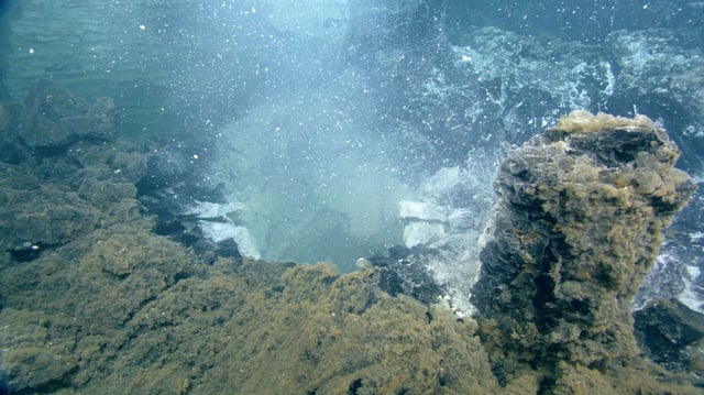 White clouds of microbial waste billow from the seafloor.