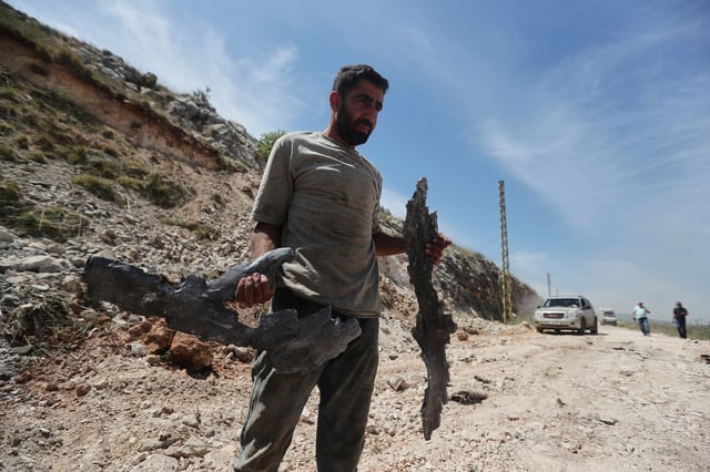A man carries parts of an Israeli missile following airstrikes that targeted hilltops near Nabatieh town, south Lebanon, Thursday, May 8, 2025. (AP Photo/Mohammed Zaatari)