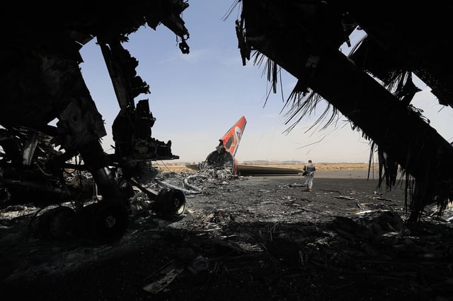 A Houthi rebel walks next to a destroyed plane at the Sanaa International Airport on Wednesday, a day after Israel's military warplanes struck Yemen's rebel-held capital Sanaa.