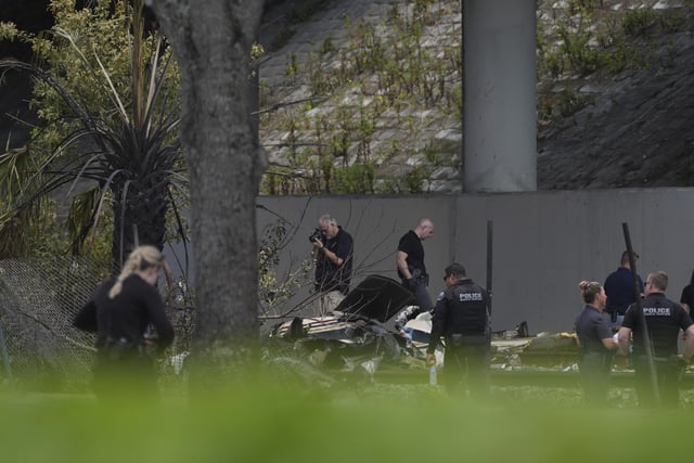 Emergency personnel respond to the area where a small plane crashed on the railroad tracks beneath the overpass near Interstate 95 in Boca Raton, Fla., on April 11, 2025. (AP Photo/Marta Lavandier)