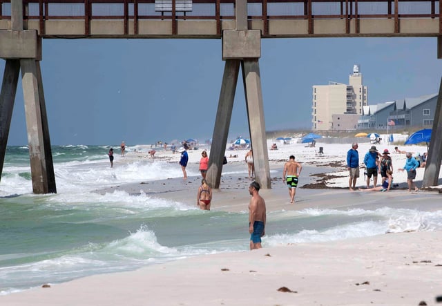 Few visitors to Pensacola Beach venture into the Gulf of Mexico as yellow flags fly over Santa Rosa Island on Wednday, April 30, 2025.