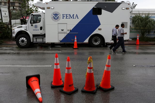 Rescue personnel walk in front of a FEMA truck in Surfside, near Miami Beach, Florida, U.S. June 30, 2021. REUTERS/Marco Bello/File Photo