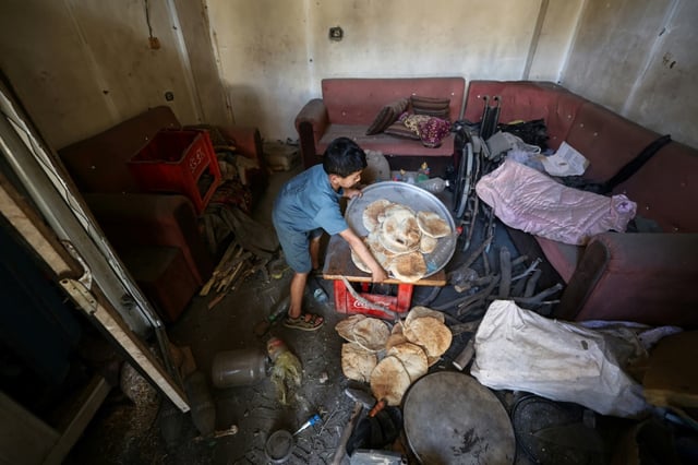 A Palestinian boy salvages bread from a makeshift bakery hit by Israeli strikes at the Nuseirat refugee camp in central Gaza