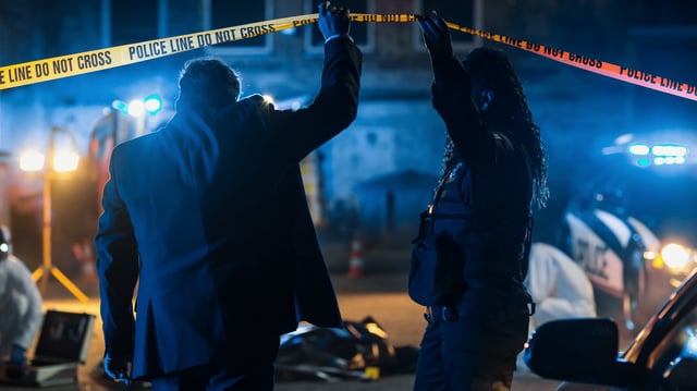 Two officers arrive at a crime scene late at night.