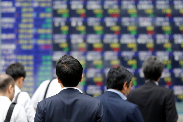 People walk past an electronic stock quotation board outside a brokerage in Tokyo, Japan, September 22, 2017.   REUTERS/Toru Hanai/File Photo