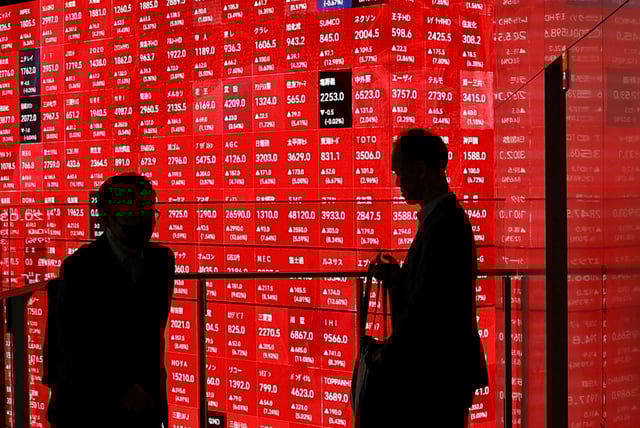 Men stand in front of an electronic stock quotation board inside a builidng in Tokyo, Japan April 8, 2025. REUTERS/Issei Kato/File Photo