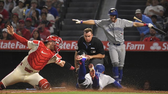 The Toronto Blue Jays’ George Springer scores under the tag of Angels catcher Logan O’Hoppe as teammate Ernie Clement, right, gestures “safe” while home plate umpire Tom Hanahan watches during the sixth inning on Thursday night at Angel Stadium. (AP Photo/Mark J. Terrill)