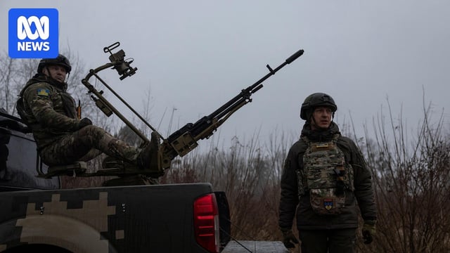 two Ukrainian soldiers operate an air defense system on the back of a truck