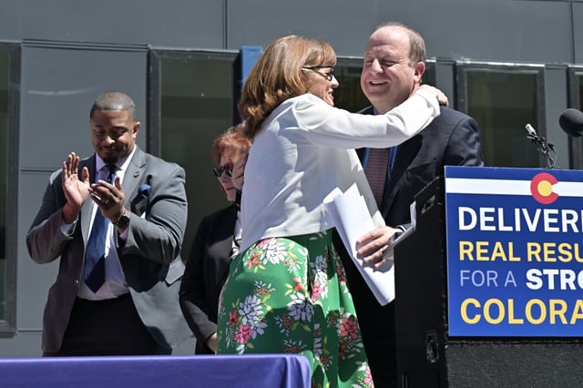 Colorado House Speaker Julie McCluskie, front left, hugs Gov. Jared Polis at a news conference where they reflected on the 2025 legislative session, which concluded Wednesday,  in front of West Holden Place Modular Housing in Denver on Thursday, May 8, 2025.  Polis signed Senate Bill 2, which is aimed at making it easier to construct factory-built structures. (Photo by Hyoung Chang/The Denver Post)