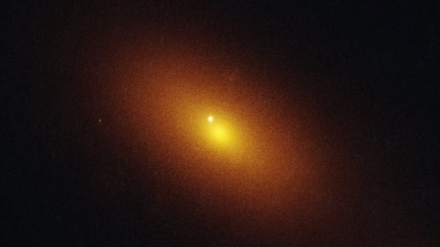 Image of a black background with a blurry orange disk at center, and a bright spot off to one side of the middle of the disk.