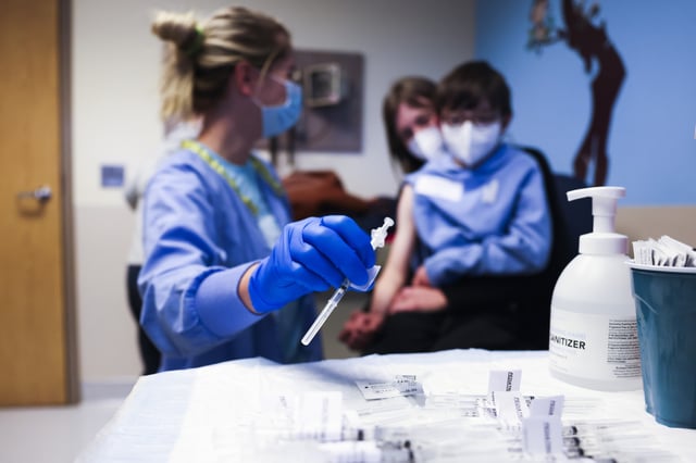 DENVER, CO - NOVEMBER 03: National Jewish Health registered nurse Emily Cole, left, prepares to give a pediatric COVID-19 vaccine to Auden Bogdan, 8, as his mother, Trish Raque, comforts him on November 3, 2021 in Denver, Colorado. The U.S. Centers for Disease Control has approved the Pfizer-BioNTech pediatric vaccine for the 28 million children aged 5-11 years old. (Photo by Michael Ciaglo/Getty Images)