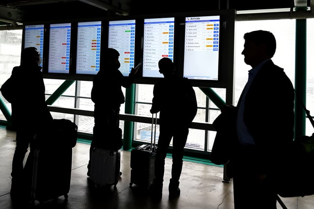 FILE - Travelers check American Airlines flight information screens for their flight status at O'Hare International Airport in Chicago, Wednesday, Feb. 22, 2023. (AP photo/Nam Y. Huh, File)