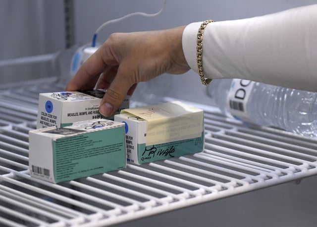Anna Hicks places the measles, mumps and rubella vaccine in a refrigerator at the Andrews County Health Department&#39;s measles clinic, Tuesday, April 8, 2025, in Andrews, Texas.