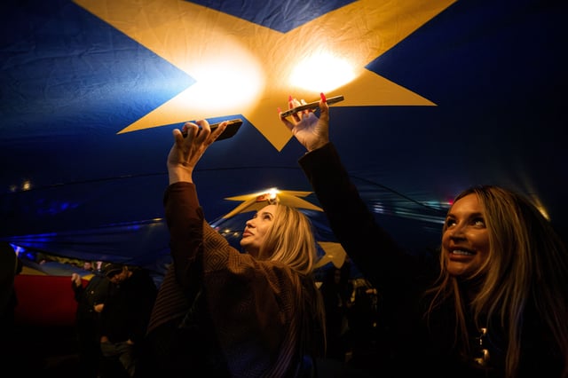 People shine the lights of their mobile phones standing under a large European Union during a pro-EU rally ahead of the second round of the presidential election redo in Bucharest, Romania, Friday, May 9, 2025. (AP Photo/Andreea Alexandru)