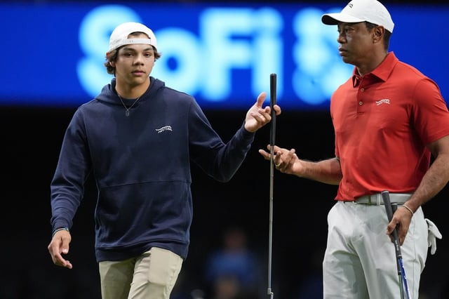 Charlie Woods, left, hands a club to his father Tiger Woods during warm-ups for a match between Tiger Wood&#39;s Jupiter Links Golf Club and Boston Common Golf, part of the TMRW Golf League (TGL), Monday, Jan. 27, 2025, in Palm Beach Gardens, Fla. (AP Photo/Rebecca Blackwell)