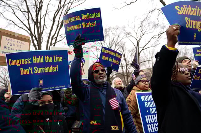 People hold signs as they gather for a "Save the Civil Service" rally hosted by a federal employee union outside the US Capitol on February 11 in Washington, DC.