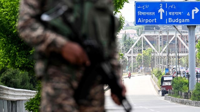 Ein indischer Soldat steht mit einem Gewehr bewaffnet an der Straße zum Flughafen Srinagar.