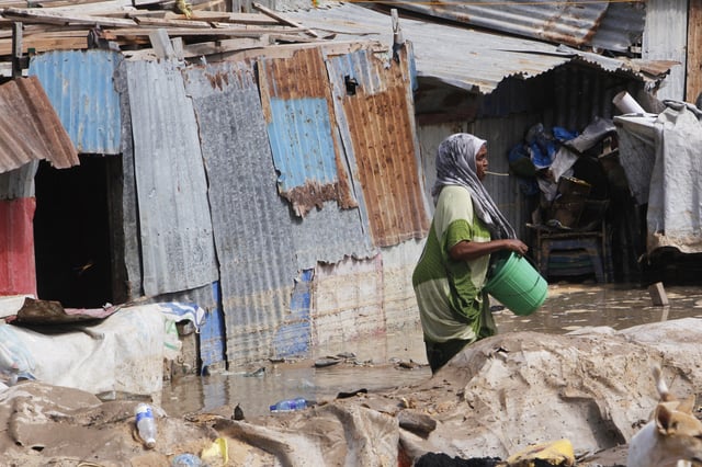 A woman stands in front of her flooded house following a heavy downpour in Mogadishu, Somalia, Saturday, May 10, 2025. (AP Photo/Farah Abdi Warsameh)