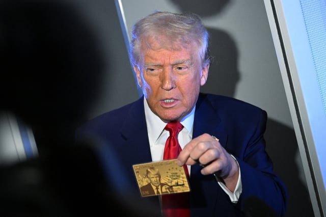 US President Donald Trump holds the $5 million dollar Gold Card as he speaks to reporters while in flight on board Air Force One, en route to Miami, Florida on April 3, 2025.