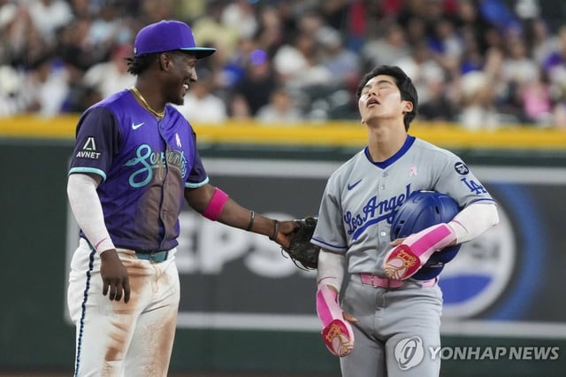 Kim Hye-seong of the Los Angeles Dodgers (R) reacts next to Arizona Diamondbacks shortstop Geraldo Perdomo after being called out at second base following a video replay during a Major League Baseball regular-season game at Chase Field in Phoenix on May 11, 2025, in this Associated Press photo. (Yonhap)
