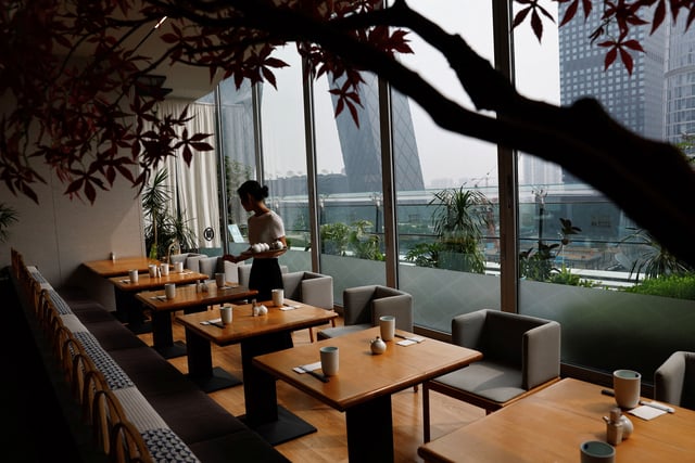 A staff member prepares tables before the business opens at a Japanese restaurant in Beijing, China September 7, 2023. REUTERS/Tingshu Wang/File photo