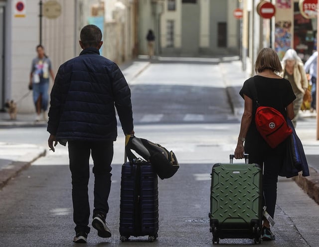 Dos turistas arrastran sus maletas por una calle de València.